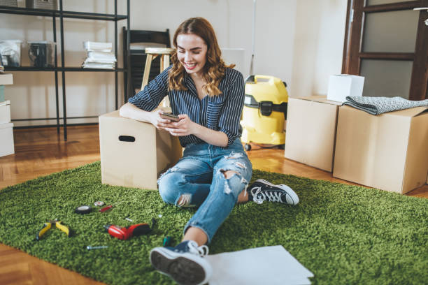 istock Gorgeous smiling girl texting in her new unpacked home 1047233984