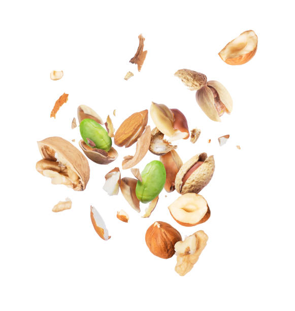 Various nuts crushed in the air, isolated on white background Various nuts crushed in the air, isolated on white background almond slivers stock pictures, royalty-free photos & images