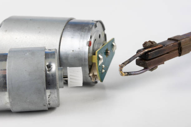 istock Repair of a small electric motor. Simple soldering work in the electronics workshop. White background. 1047244478