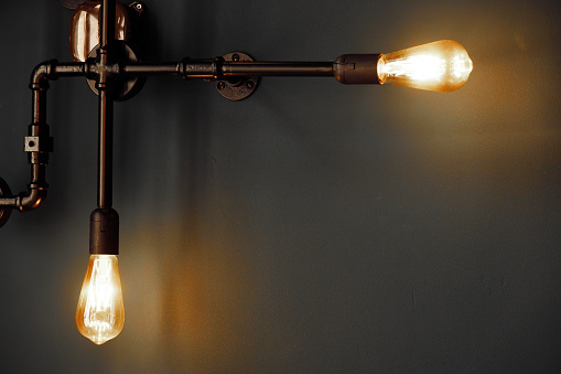 two orange retro bulb lamp with black metal pipe in the dark night on grey wall interior background
