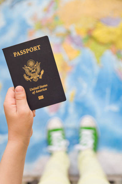 istock Child's hand holding US passport. Map background. Ready for traveling. Open world. 1047262076