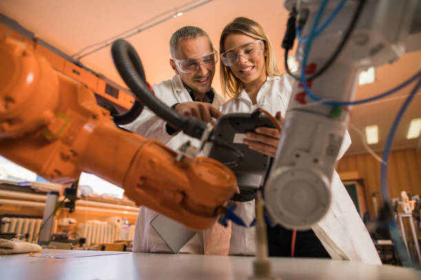 istock Below view of happy scientist cooperating while working on robotic arm in laboratory. 1047264918