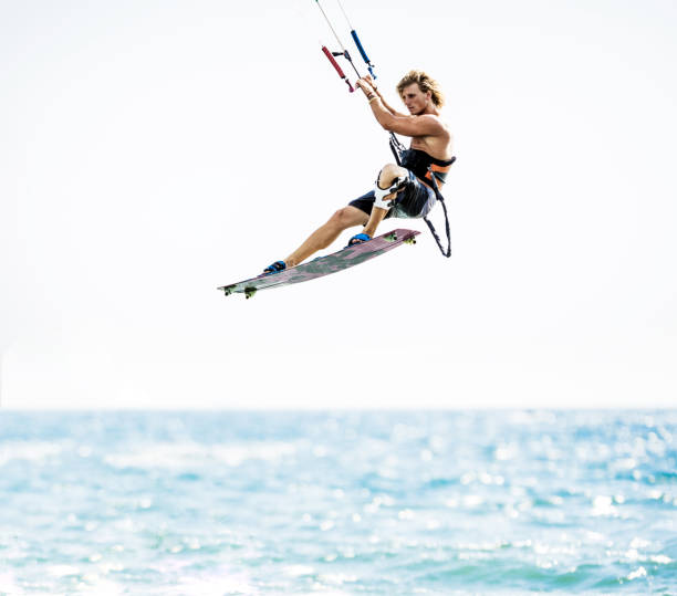 Young athletic man kitesurfing in mid-air during summer day at sea. Copy space.