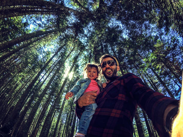 istock Father and daughter in a forest taking selfie group portrait 1047296866
