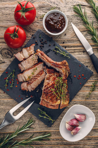 Sliced grilled veal chop with vegetables on rustic table. Top view stock photo