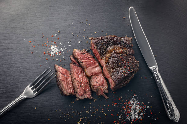 Sliced beef steak sous-vide sliced on slate board with cutlery stock photo