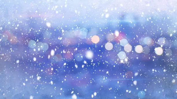 Photo of snowfall and defocused lights evening wintry city