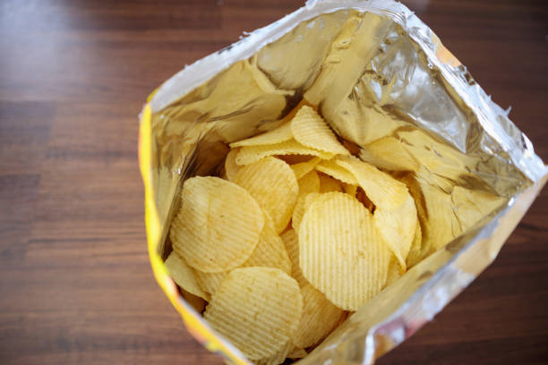 istock Potato chips in open snack bag close up on table floor 1047316666