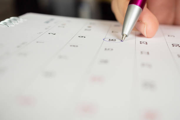 istock female hand holding pen circle mark on calendar page 1047316722