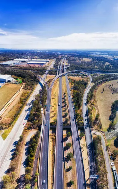 Multiple multi-lane motorways along M7 at Lighthorse interchange in Sydney West crossing Motorway 4 - aerial vertical panorama from ground surface to horizon.