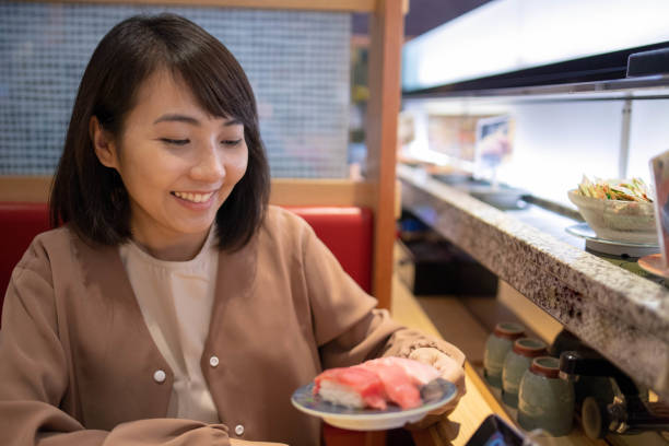 アジア観光レストランで寿司を食べて - 回転寿司 ストックフォトと画像