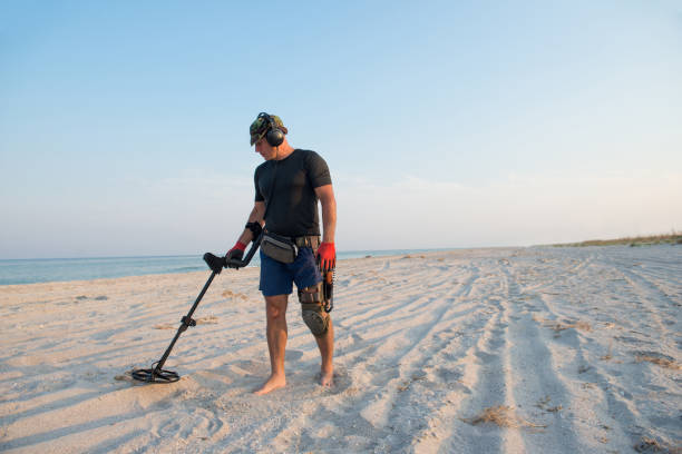 istock Man with a metal detector on a sea sandy beach 1047330222