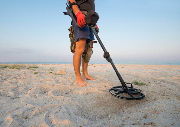istock Man with a metal detector on a sea sandy beach 1047330404