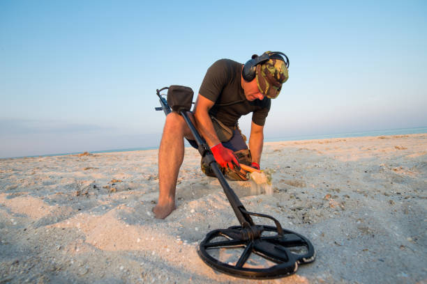 homem com um detector de metais em uma praia de areia do mar - ancient weapon audio - fotografias e filmes do acervo