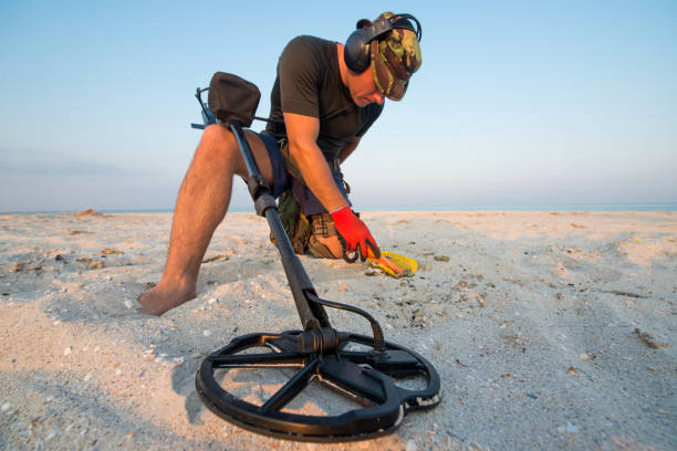 homem com um detector de metais em uma praia de areia do mar - ancient weapon audio - fotografias e filmes do acervo