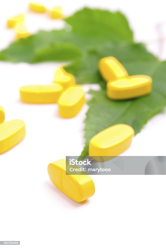 Giallo vitamina pillole su foglie verdi - Foto stock royalty-free di Antibiotico