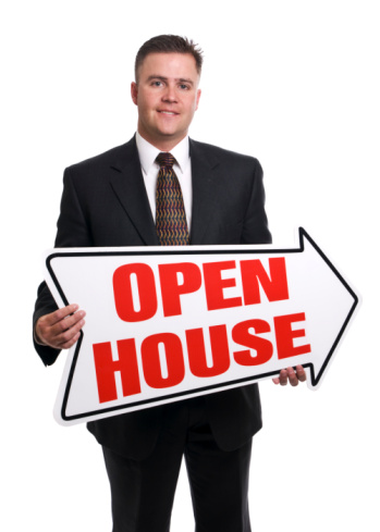 Real Estate Agent holding open house sign while smiling and looking at camera. Isolated in camera, not cut out.