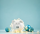 Piggy bank wrapped in a string of Christmas lights