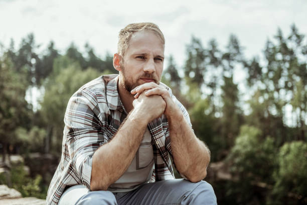 istock Man feeling relieved while sitting on his own surrounded by mountains and trees 1047407252