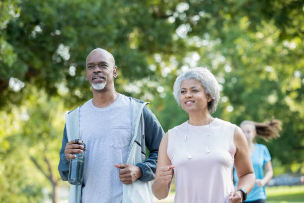 bella coppia senior che fa jogging all'aperto insieme - senior adult senior couple exercising african ethnicity foto e immagini stock