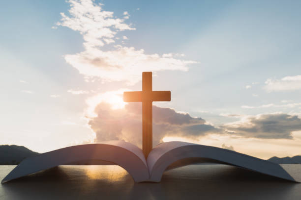 istock open Bible, script in blur with focus on palm cross,on sunrise background, Crucifix, Symbol of Faith. 1047424308