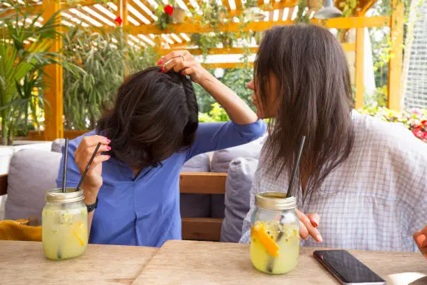 A woman is showing her hair in a summer cafe, on a table lemonade. Concept of leisure and conversation.