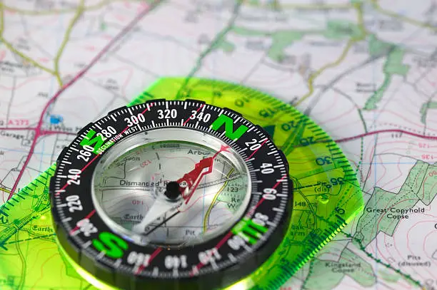 A compass with marked degrees and a north heading on a paper map.