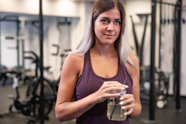 istock Young Woman Drinking Protein Drink in Gym After Workout 1047431232