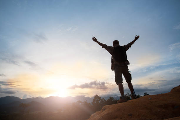 istock Man silhouette stand alone on the mountain and watching romantic colorful sunrise 1047431284
