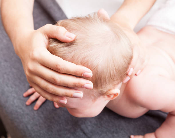 petit bébé recevant un traitement ostéopathique de son crâne et du cou - photo manipulation photos photos et images de collection