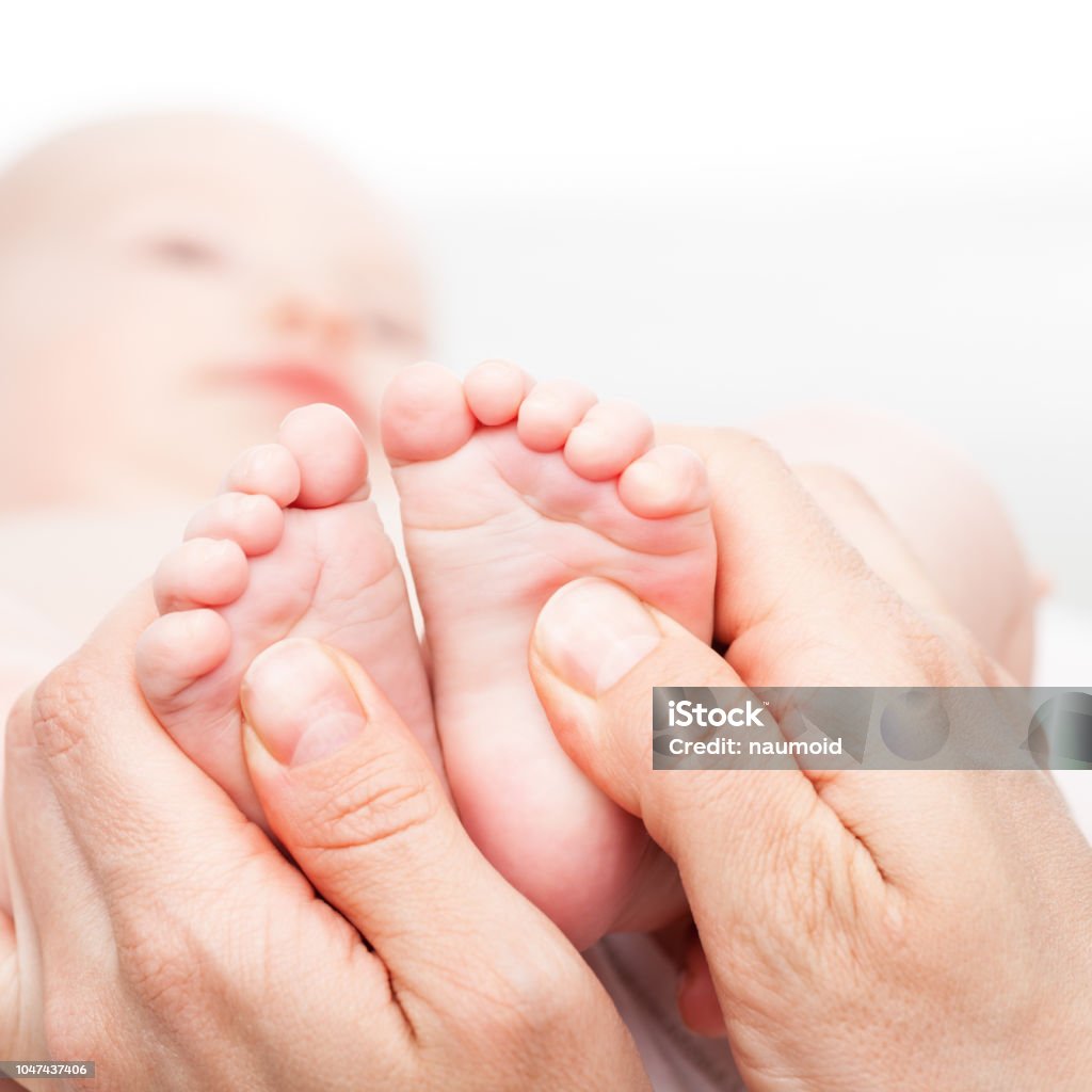 Little baby receiving chiropractic or osteopathic foot massage Close-up shot of three month baby girl's foot manipulated by osteopathic manual therapist or physician Baby - Human Age Stock Photo