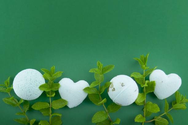 istock Mint bath bombs.Organic body cosmetics with mint extract. bath bombs round and heart form with mint extract and twigs of mint on bright green background. 1047446272
