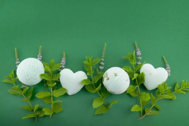 Mint bath bombs.Organic body cosmetics with mint extract. bath bombs round and heart form with mint extract and twigs of fresh mint on green background.