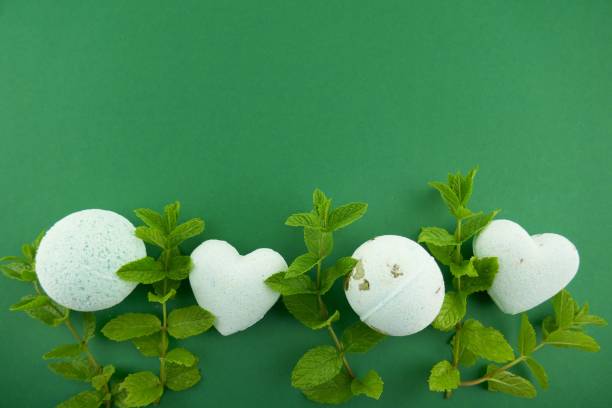 istock Mint bath bombs. body cosmetics with mint extract. bath bombs round and heart form with mint extract and twigs of fresh mint on bright green background. 1047448310