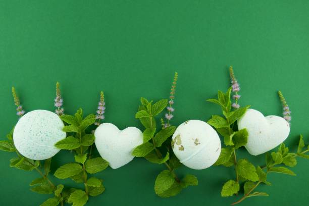istock Mint bath bombs.Organic body cosmetics with mint extract. bath bombs round and heart form with mint extract and twigs of fresh mint on bright green background. 1047448312