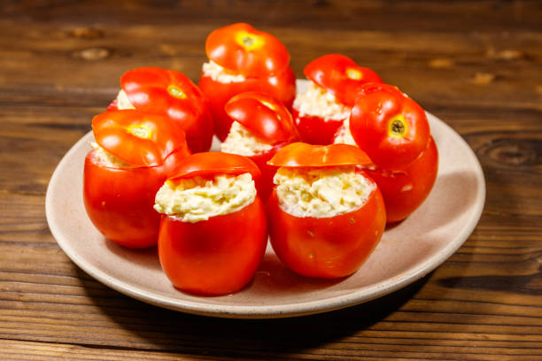 istock Tomatoes stuffed with cheese on wooden table 1047448318