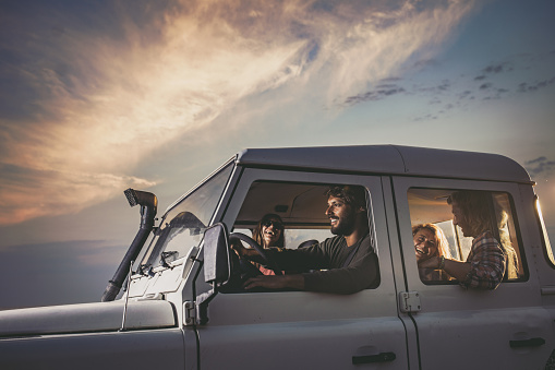 Young happy couples having fun while going on a road trip by truck. Copy space.