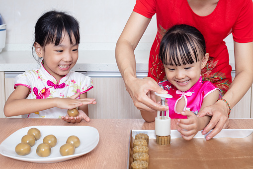 Asian Chinese mother and daughters making moon cake in the kitchen at home