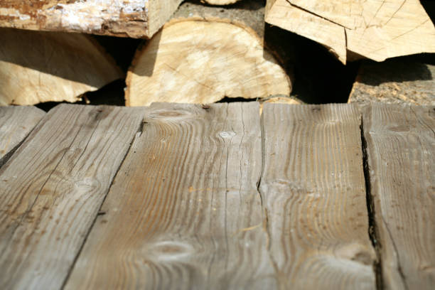 Empty wooden deck table with pile of firewood in backround