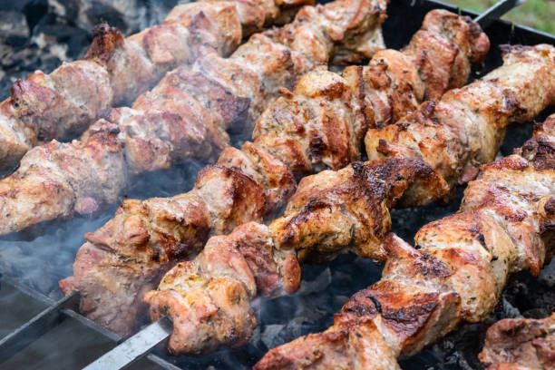 istock Frying pork on a skewer over a brazier. Turning meat over coals. Appetizing shish kebab. 1047459890