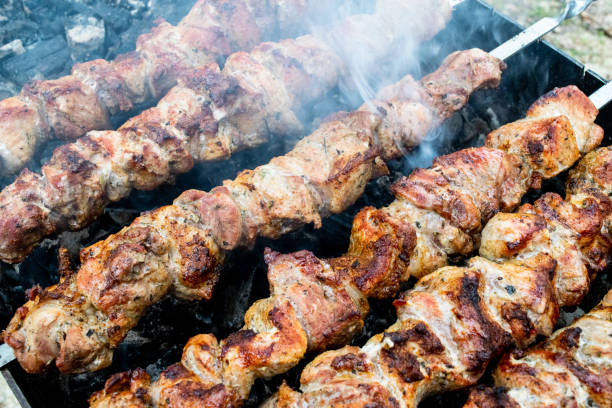 Frying pork on a skewer over a brazier. Turning meat over coals. Appetizing shish kebab.