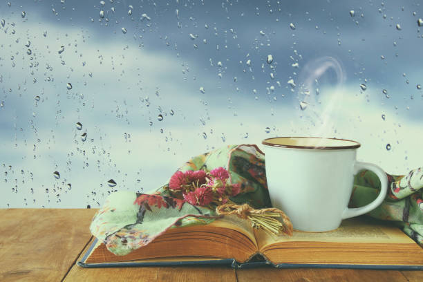 istock coffee cup on a rainy day over wooden table and window with rain drops background. 1047460028