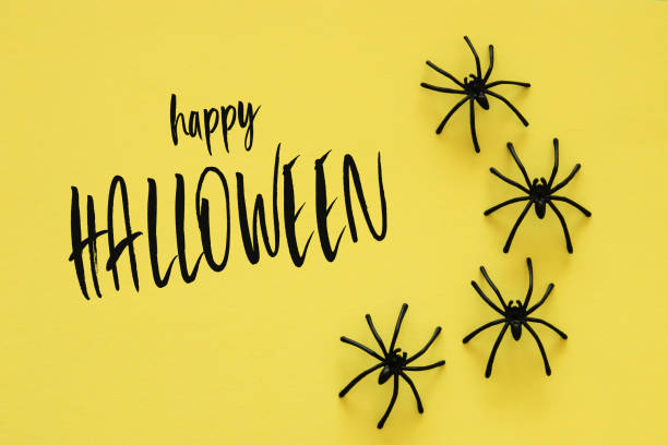 istock Halloween holiday concept. Black spiders over yellow background. Top view, flat lay. 1047460078