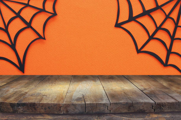 istock Halloween holiday concept. Empty rustic table in front of Spider webs over orange background. Ready for product display montage. 1047460146