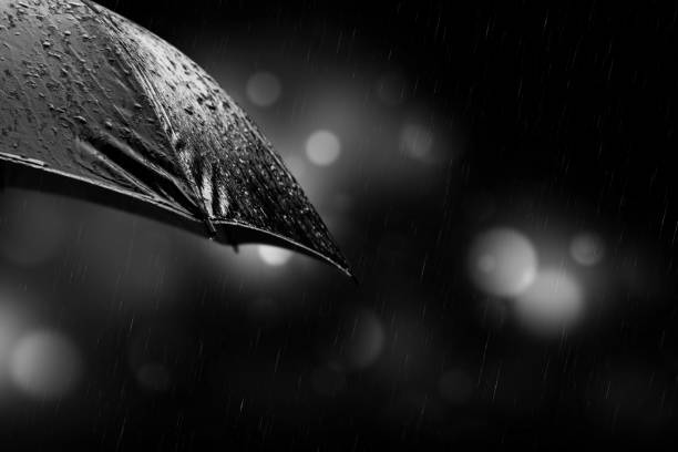 istock Rain drops from a black umbrella concept for bad weather on night background 1047465330