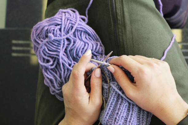 istock Knitting. Female hands with knitting needles. Top view. Close-up. 1047475578