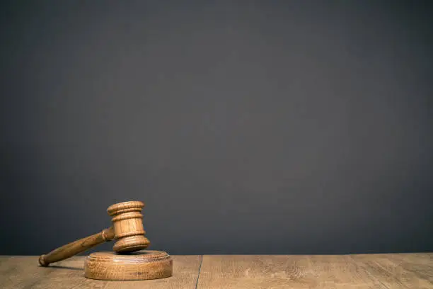 Photo of Retro auction or judge wooden gavel in front black wall background. Symbol of justice. Vintage old style filtered photo