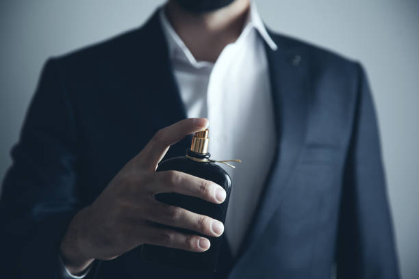 Handsome young man using perfume Handsome young man using perfume perfume stock pictures, royalty-free photos & images