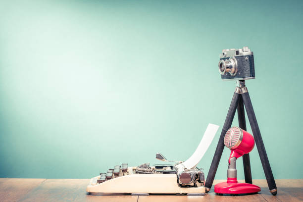 retro typewriter, outdated film photo camera on tripod and old microphone on wooden table front mint green wall background. blogging concept. vintage style filtered photo - writing typewriter 1950s style retro revival imagens e fotografias de stock