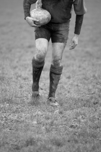 Black & White image of a rugby player kicking the ground to make a kicking tee for the ball.